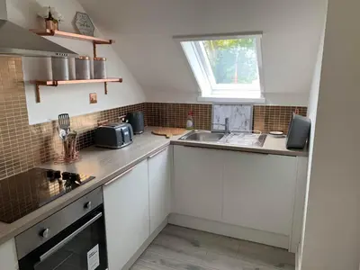 a kitchen with white cabinets and a sink and a window at The Clachan Flat in Rosneath