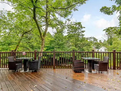 a patio with tables and chairs on a wooden deck at Dalgarven Spa House in Dalry