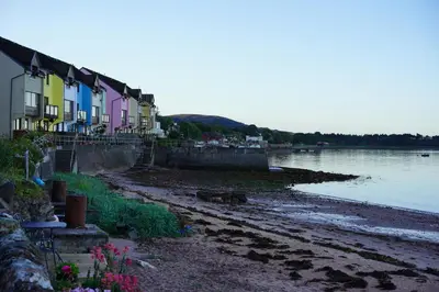 a row of houses on the shore of a body of water at Beach house no2 with amazing sea views and private garden onto beach. in Fairlie