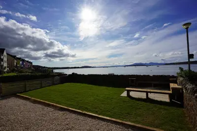 a park with a bench next to a body of water at Beach house no2 with amazing sea views and private garden onto beach. in Fairlie