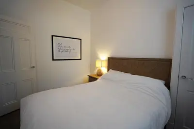 a bedroom with a white bed and a picture on the wall at Beach house no2 with amazing sea views and private garden onto beach. in Fairlie
