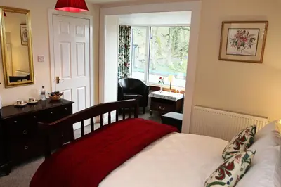 a bedroom with a bed and a desk and a window at Elderslie Guest House in Oban