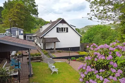 a white house with a garden and flowers at Elderslie Guest House in Oban