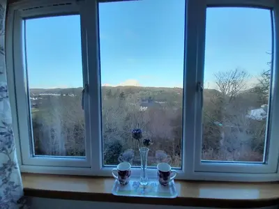 a table with two windows with a vase and two cups at Elderslie Guest House in Oban