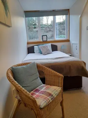 a bedroom with a bed and a chair and a window at Elderslie Guest House in Oban