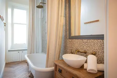 a bathroom with a sink and a tub and a mirror at Oakshaw Apartment in Paisley