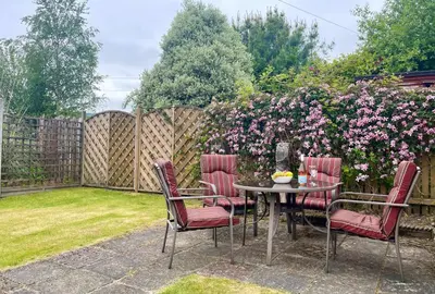 a patio with a table and chairs and a fence with flowers at Freeland Cottage in Dunoon