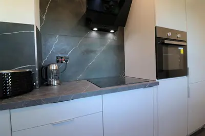 a kitchen with white cabinets and a black counter top at Jess View in Renfrew