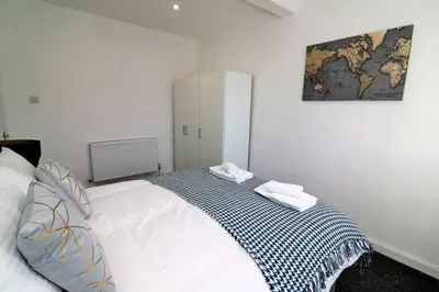 a bedroom with a large white bed with a map on the wall at Jess View in Renfrew