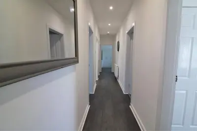 a hallway with white walls and a mirror on the wall at Jess View in Renfrew