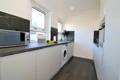 a kitchen with white cabinets and a washer and dryer at Jess View in Renfrew