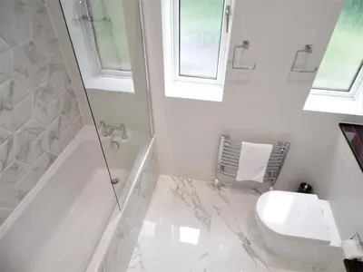 a white bathroom with a shower and a toilet at Penilee Upper Apartment in Glasgow
