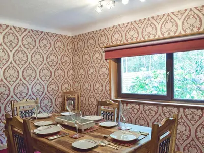 a dining room with a table with chairs and a window at Glen Rosa in Ayr