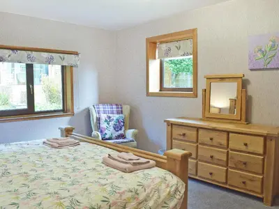 a bedroom with a bed and a dresser and a mirror at Glen Rosa in Ayr