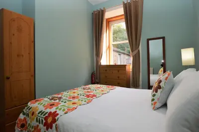 a bedroom with a bed with a flower blanket on it at Keek Oot at 73 in Gourock