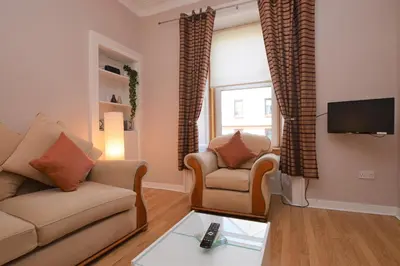 a living room with a couch and two chairs and a tv at Keek Oot at 73 in Gourock
