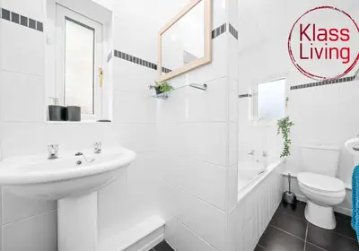 a white bathroom with a sink and a toilet at Nicol Apartment by Klass Living Airdrie in Airdrie