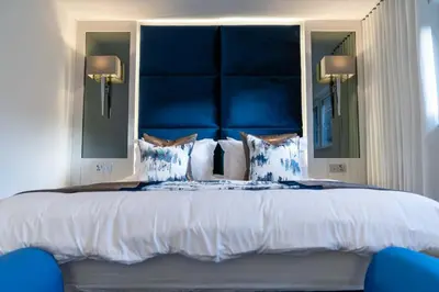 a large bed with a blue headboard and pillows at The Shore in Queensferry