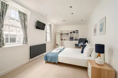 a bedroom with a bed and a tv on the wall at Queensferry Street Lane - Fantastic 2 BR City Centre Mews House with free secure parking! in Edinburgh