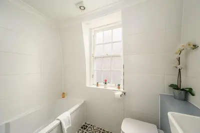 a white bathroom with a tub and a sink at Queensferry Street Lane - Fantastic 2 BR City Centre Mews House with free secure parking! in Edinburgh