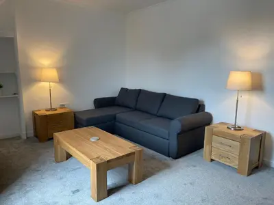a living room with a blue couch and two tables at Premier Apartment D in Broxburn