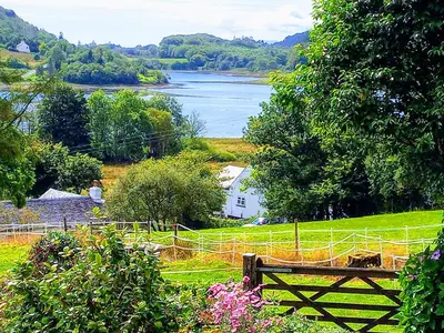a bench in a field with a view of a lake at Granite Croft in Appin