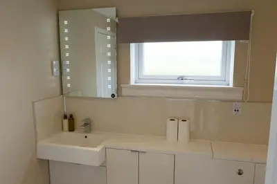 a white bathroom with a sink and a window at Bachilton Farm Holidays in Perth