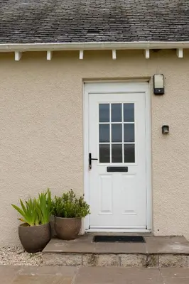 a white door of a house with two plants at Bachilton Farm Holidays in Perth