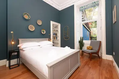 a bedroom with a white bed and a blue wall at 16 1 Eildon Street in Edinburgh