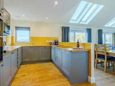 a kitchen with grey cabinets and a table and chairs at Invernahyle Cottage in Acharra