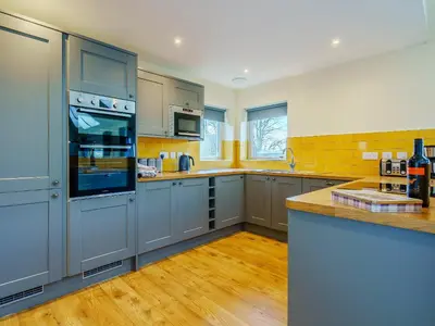 a large kitchen with blue cabinets and wooden floors at Invernahyle Cottage in Acharra