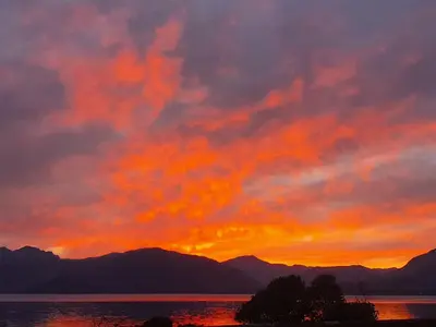 a sunset over a body of water with mountains at Sea Otter Cottage in Appin