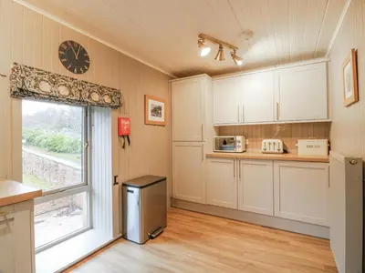 a kitchen with a window and a clock on the wall at The Coach House - Holmwood in Glasgow