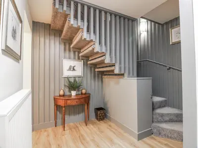 a winding staircase in a home with a wooden table at The Coach House - Holmwood in Glasgow