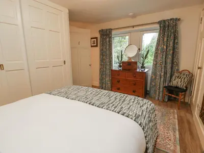 a bedroom with a bed and a dresser and a window at The Coach House - Holmwood in Glasgow