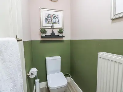 a bathroom with a white toilet and green walls at The Coach House - Holmwood in Glasgow