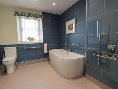 a bathroom with a tub and a toilet and blue tiles at Royal Artillery Cottage - Culzean Castle in Maybole