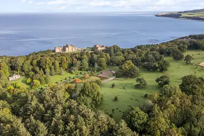 an aerial view of a castle on a hill next to the water at Royal Artillery Cottage - Culzean Castle in Maybole