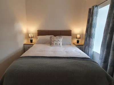 a bedroom with a bed with two lamps and a window at 2-Bed Barn Hot Tub & Pet Friendly near Muirkirk in Cumnock