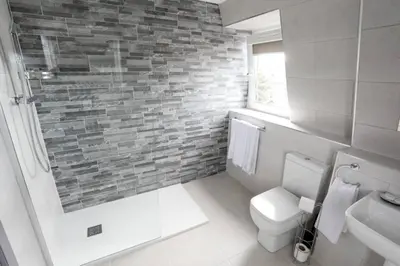 a bathroom with a white toilet and a brick wall at Broadcroft Hotel in Kirkintilloch