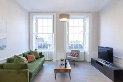 a living room with a green couch and a tv at Dragon Suites - Edinburgh City Centre 1 Bed Apartment in Edinburgh