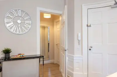 a hallway with a white door and a clock on the wall at Dragon Suites - Edinburgh City Centre 1 Bed Apartment in Edinburgh
