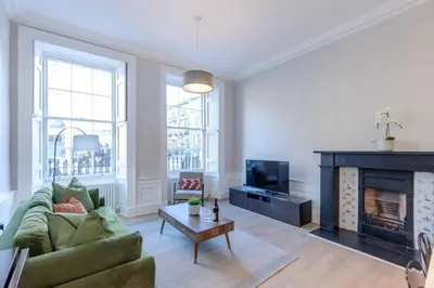 a living room with a green couch and a fireplace at Dragon Suites - Edinburgh City Centre 1 Bed Apartment in Edinburgh