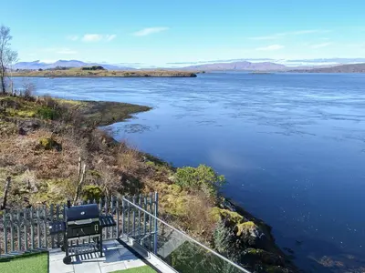 a view of a river with two chairs on a balcony at 4 Dolphins in Connel
