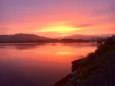 a sunset over a body of water with the sun setting at 4 Dolphins in Connel