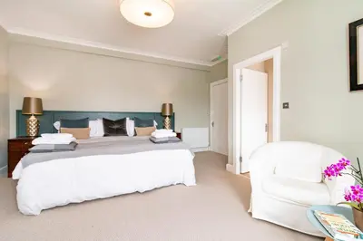 a bedroom with a large bed and a white chair at Black Bull Gartmore in Stirling