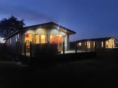 a small house is lit up at night at 2 Bedroom Sleeps 4 Lodge-Smart Tv-Hot tub-Dogs Ok in Lochwinnoch