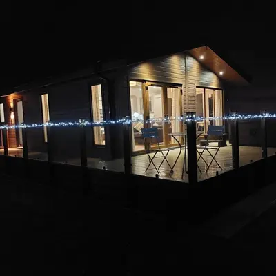 a house with christmas lights on it at night at 2 Bedroom Sleeps 4 Lodge-Smart Tv-Hot tub-Dogs Ok in Lochwinnoch