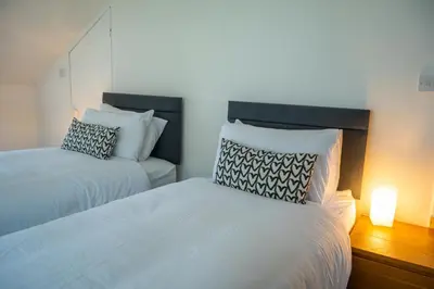 a bedroom with two beds and a lamp on a table at No 2 Planetree in Lochgoilhead