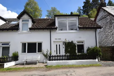 a white house with a bench in front of it at No 2 Planetree in Lochgoilhead